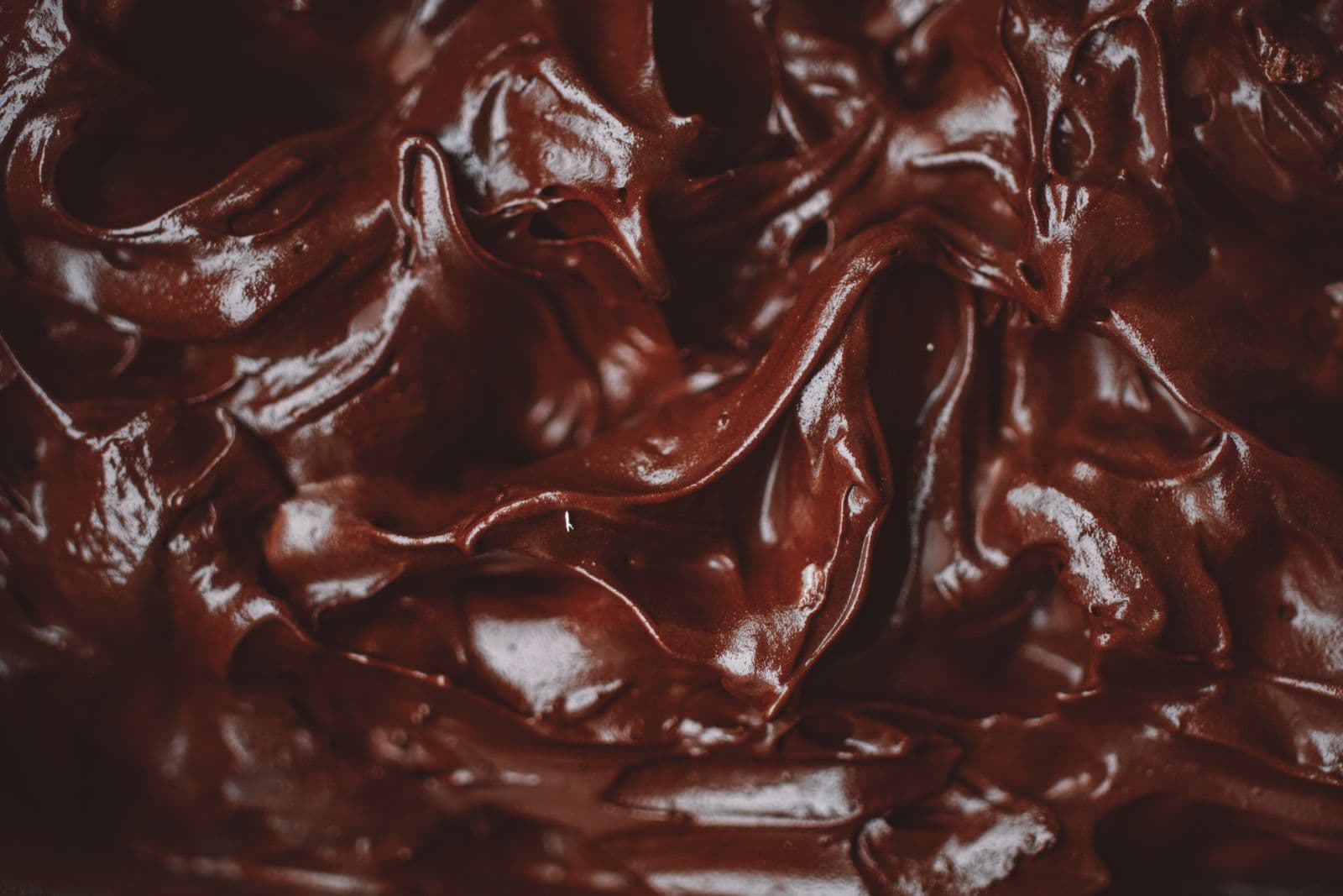Macro close-up of glossy, rippled dark chocolate ganache