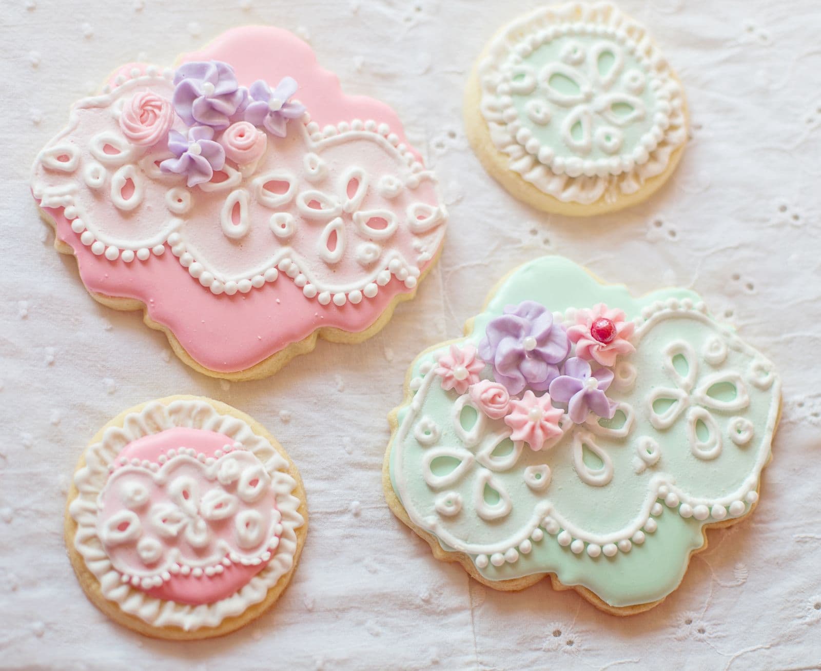 Elaborately hand-piped royal icing cookies in lace and floral designs